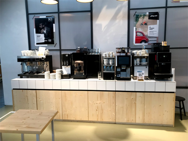 Messestand Kaffeewerkstatt, Stahlregale, Werkstattwagen, Klicklinoleum, geflieste Theke, Durchreiche, verputzte Kabine, Fenster, Anlehnhocker, Beistelltische